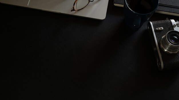 Dark leather top workspace desk with laptop and vintage camera