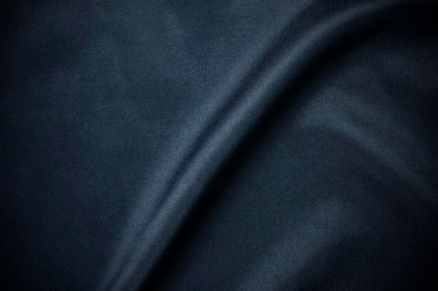 Текстура темной роскошной гладкой одежды элегантный темно-синий цвет шелковой ткани в качестве фона