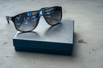 Dark male sunglasses on grey concrete surface Stock Photo by FabrikaPhoto