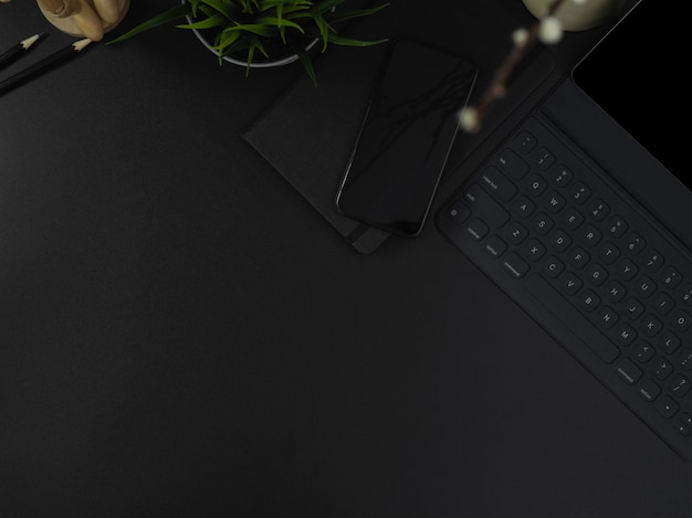 Dark modern office desk with digital devices, stationery, decorations and copy space