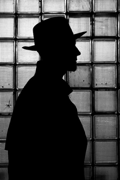 Dark mystical silhouette of a man in a hat at night in retro noir style