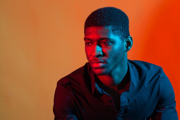 Dark neon portrait of young man wearing in shirt. Red and blue light. Technology