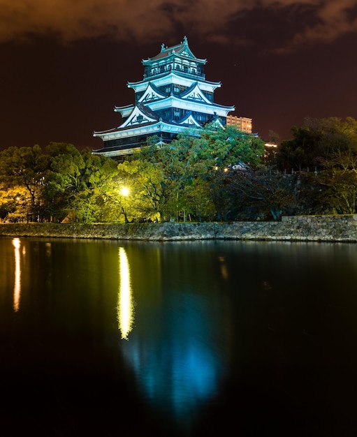 A dark night scene with a castle and the lights reflecting on the water.