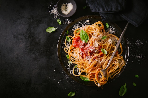 Piatto scuro con spaghetti italiani su oscurità