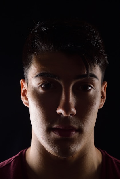 Dark portrait of a young man on black background