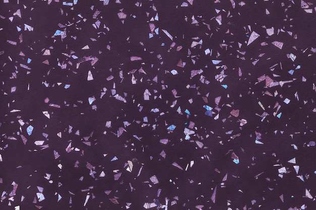 Dark purple sparkling background from small foil sequins, closeup. Violet texture backdrop with small crumb pattern.