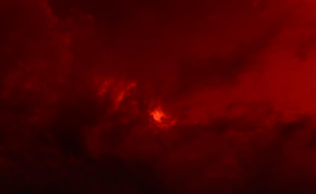 Dark red dramatic clouds with sun glare. Natural background and texture