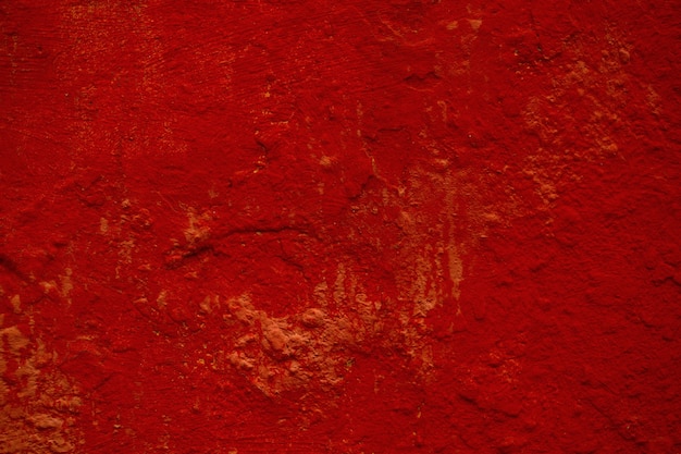 Photo dark red  texture of a painted wall with rough surface and stains in a full frame view.