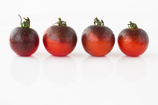 Dark red tomatoes with water droplets on a white