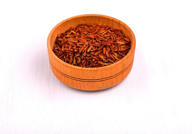 Dark rice in a wooden cup on a white dining table.