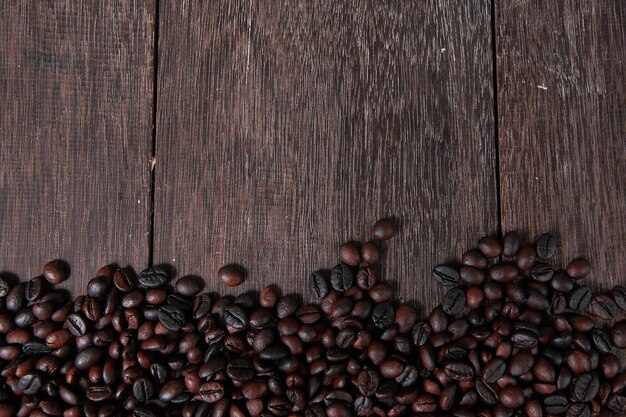 Photo dark roasted coffee beans on dark old wooden table texture