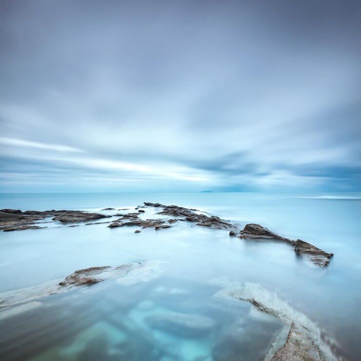 Photo dark rocks in a blue ocean under cloudy sky in a bad weather