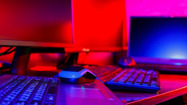 네온 불빛이 있는 게이머를 위한 어두운 방. 컴퓨터 게임, 게임 스포츠 및 스트림을 위한 인테리어입니다. 내부에 추상 네온 배경입니다. 게임존. 파란색과 분홍색 네온
