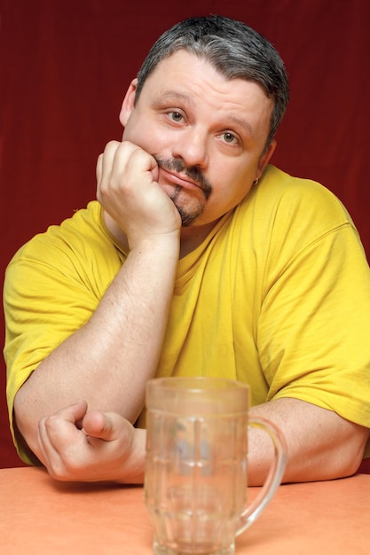 Dark sad man looks at an empty beer mug