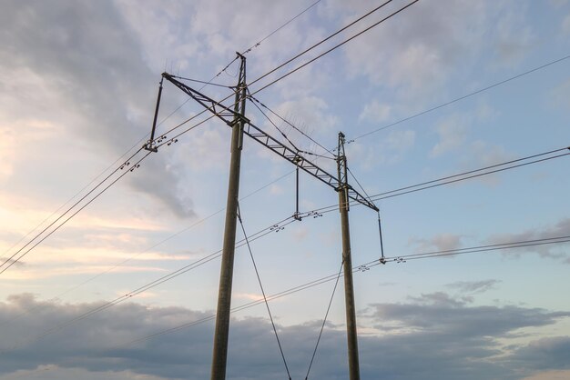 Dark silhouette of high voltage tower with electric power lines at sunrise.