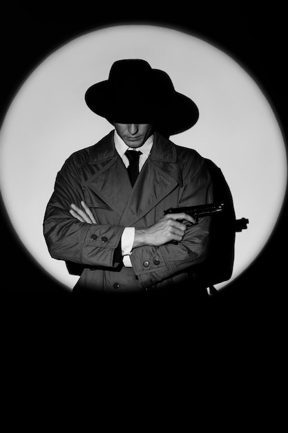 1950 年代のノワール スタイルの映画で銃を持ったコートと帽子の男性探偵の暗いシルエット