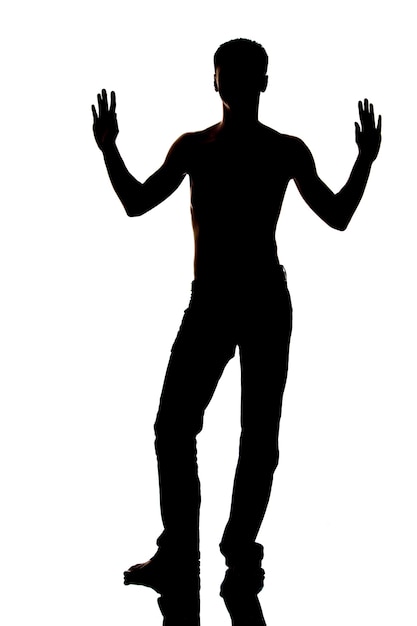 Photo dark silhouette of man in jeans and naked torso with hands up, on white background