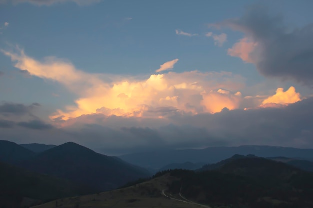 オレンジ色の雲と夕日を背景に山の暗いシルエット