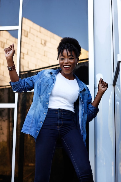 Dark-skinned American woman is happy and dancing on a blue space