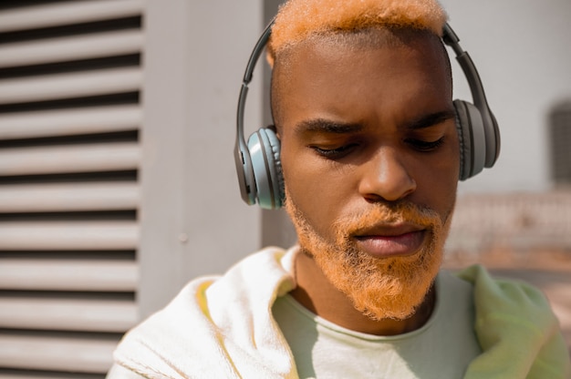 A dark-skinned bearded young man in headphones