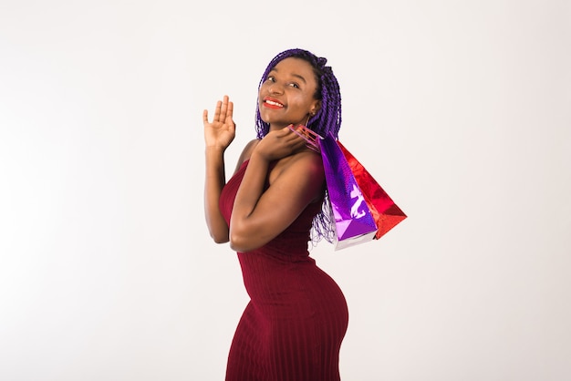 A dark-skinned girl holds packages with new purchases, smiles and looks at the camera. The girl is happy shopping, shopping