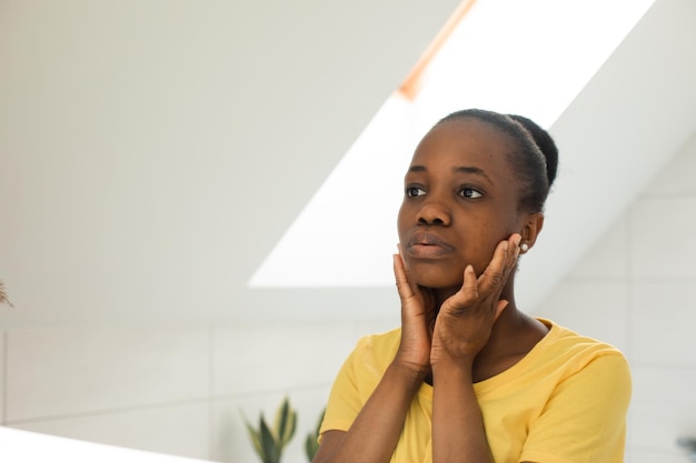 Dark skinned girl looking into mirror touching cheeks