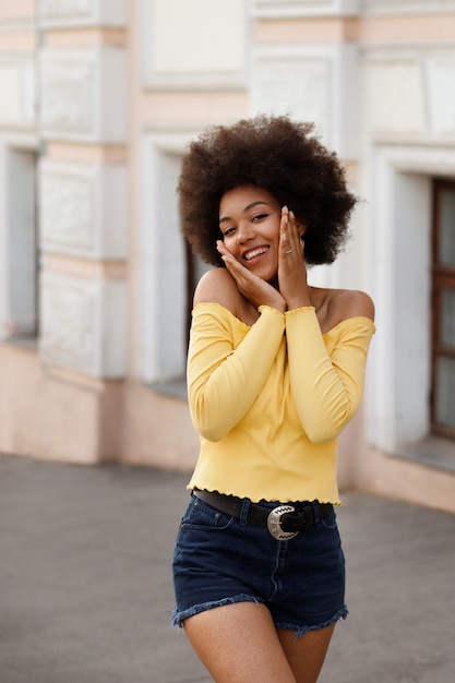 Dark-skinned girl in yellow top smiles on a summer walk