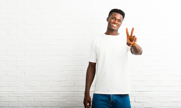 Dark skinned man smiling and showing victory sign