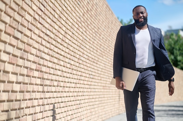 A dark-skinned man walking along the brick wall