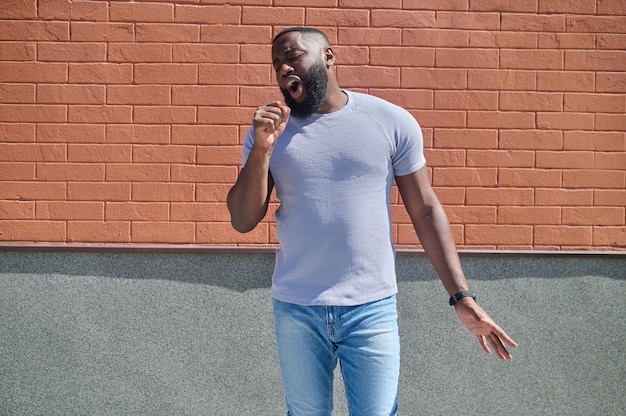 A dark-skinned man in a white tshirt and jeans feeling good