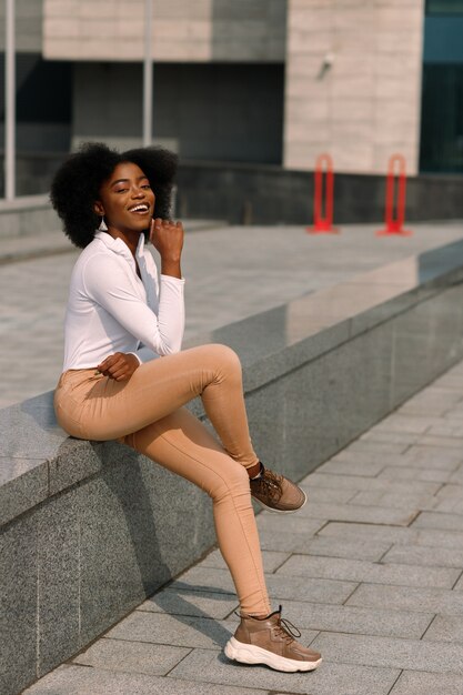 Photo dark-skinned sits in the city and smiles