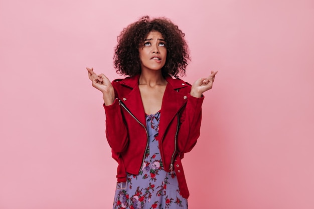 Dark-skinned woman crossed her fingers on pink wall