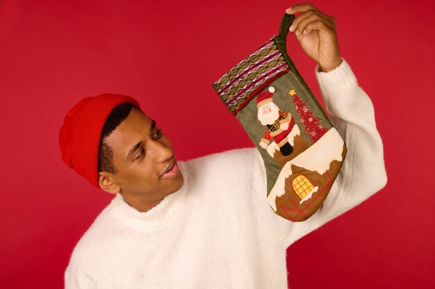 A dark-skinned young guy holding xmas stockings