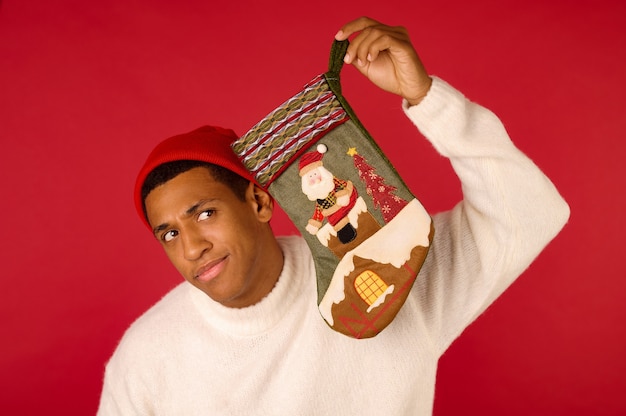 A dark-skinned young guy with a xmas stocking in hands