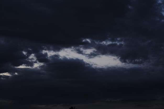 A dark sky with clouds and a blue light in the middle