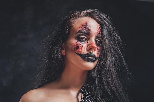 In the dark, smoky photo studio young girl has a photo shoot in a role of creepy clown.