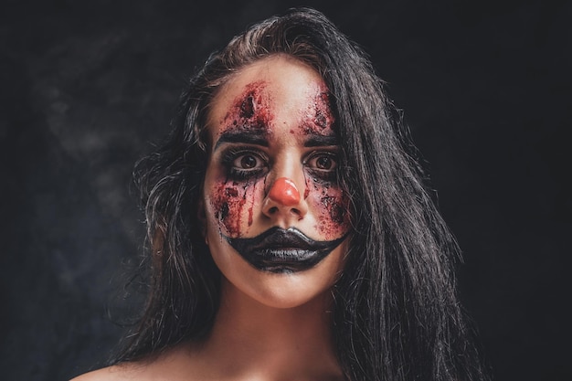 In the dark, smoky photo studio young girl has a photo shoot in a role of creepy clown.