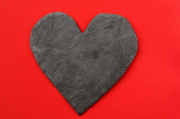 Dark stone heart on red background