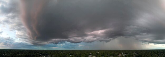 Dark stormy clouds forming on gloomy sky before heavy rainfall over suburban town area