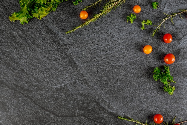 Dark surface with cherry tomato, parsley and rosemary