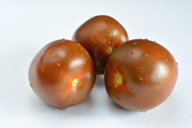 dark tomatoes with drops of water on a white background isolated macro