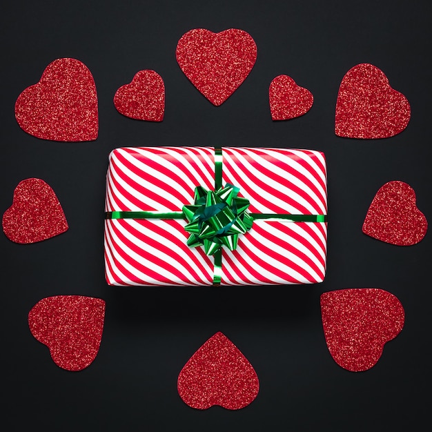 La carta di san valentino scuro con cuori rossi e regalo di festa con nastro verde. san valentino o la festa di san valentino.