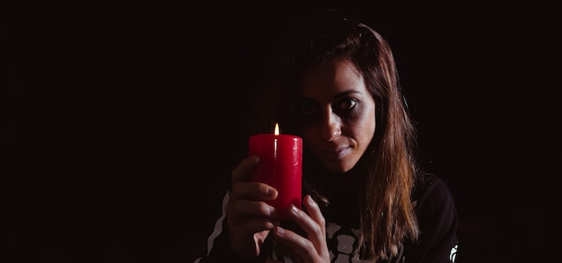 Dark woman holding a candle on halloween. Night of the dead. Copy space. Selective focus.