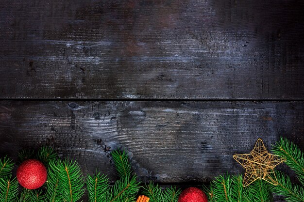 Dark wooden background with fir branches and christmas decorations top view space for text