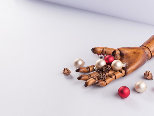 Dark wooden hand with xmas tree ornament on gray