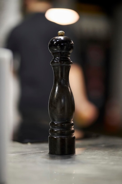 dark wooden pepper grinder on the table, blurred background. wooden salt shaker on bokeh background.