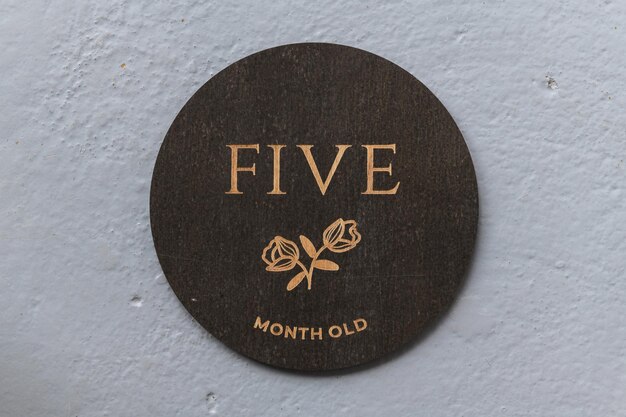 Dark wooden round board with the inscription five on a gray background