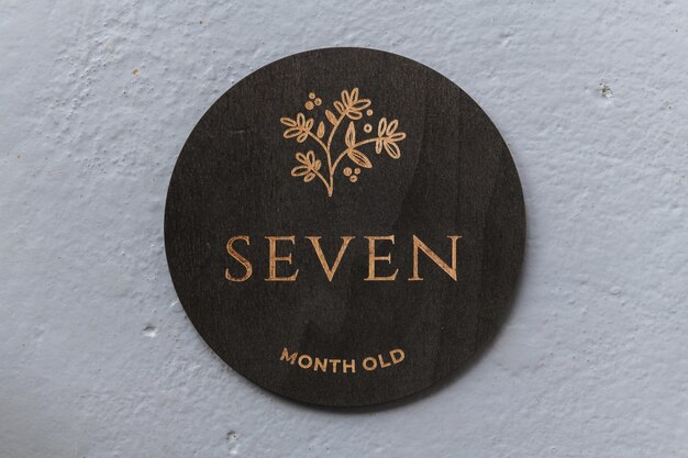 Dark wooden round board with the inscription seven on a gray background