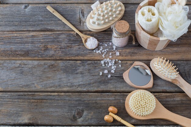 on a dark wooden table items for a bath: sea salt, brushes, washcloths 