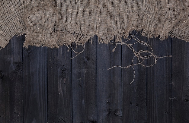 Dark wooden table with burlap, top view